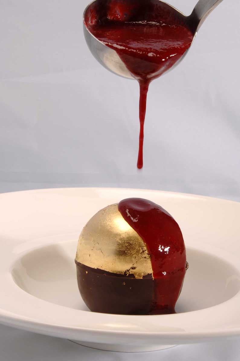 Schokolade-Kugel „Surprise“ mit Blattgold verziert und mit Coulis serviert